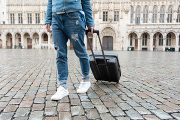 Woman tourist goes with a suitcase at the Grand Place in Brussels, Belgium
