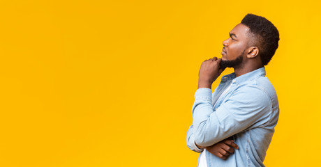 Young african american guy thinking about something over yellow background - Powered by Adobe