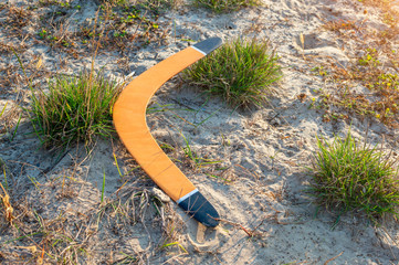 Australian boomerang lies on the sandy ground. The concept of countryside recreation and outdoor activities. evening view - obrazy, fototapety, plakaty