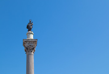 Fototapeta na wymiar A corinthian column with Madonna and the child on the top and a blue sky in the background