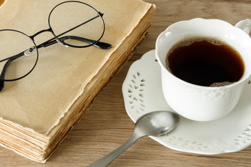 A book with old-fashioned glasses and cup of coffee