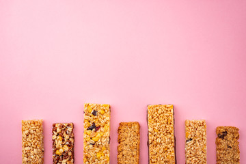 Row of assorted granola bars on pink background