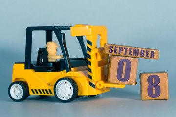 september 8th. Day 8 of month, Construction or warehouse calendar. Yellow toy forklift load wood cubes with date. Work planning and time management. autumn month, day of the year concept