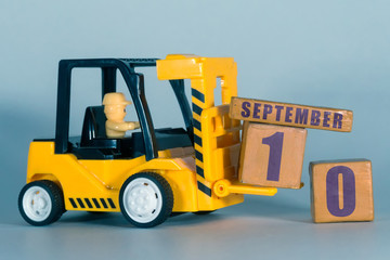 september 10th. Day 10 of month, Construction or warehouse calendar. Yellow toy forklift load wood cubes with date. Work planning and time management. autumn month, day of the year concept