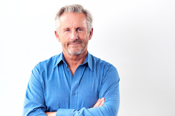 Studio Shot Of Mature Man Against White Background Smiling At Camera