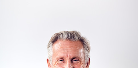 Obraz premium Studio Shot Of Mature Man Against White Background Laughing At Camera Cropped Below Eyes