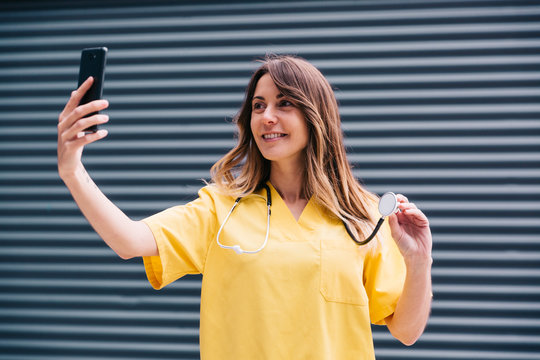 Chica joven haciendose un selfie con su smartphone durante su descanso en el trabajo de enfermera.