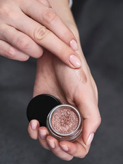 Woman's beauty blogger hands holding bottles and tubes spa professional hi-end cosmetics applies...