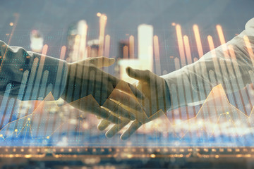 Double exposure of financial chart on cityscape background with two businessmen handshake. Concept of financial analysis and investment opportunities