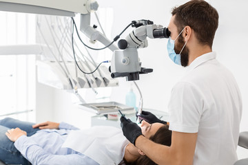 Side view of professional dentist using modern technologies in treatment