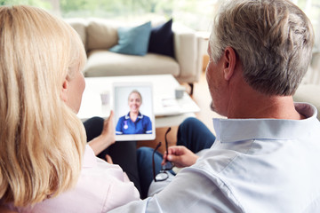Mature Couple Having Online Consultation With Female Nurse At Home On Digital Tablet