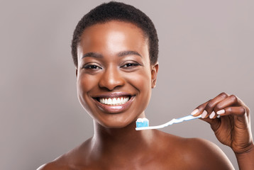 Happy african american girl holding toothbrush with applied toothpaste - Powered by Adobe