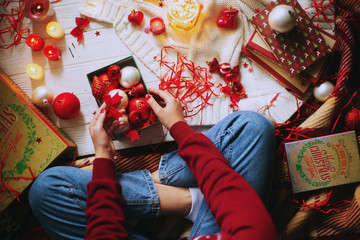 Celebrating New Year and Christmas at home, a girl wraps and holds gifts in a cozy atmosphere