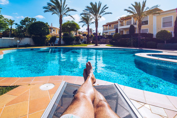 Relaxing at the swimming pool. Man relaxing next to swimming pool. Man enjoying the hot summer at...