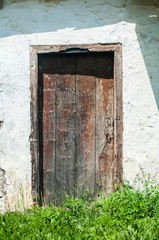 Old weathered aged rural wooden house door closeup in sunny day