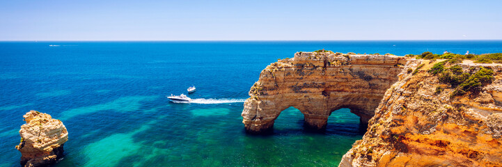 Natürliche Höhlen am Strand von Marinha, Algarve Portugal. Felsklippenbögen am Strand von Marinha und türkisfarbenes Meerwasser an der Küste Portugals in der Region Algarve.