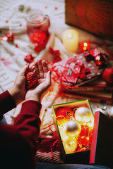 Celebrating New Year and Christmas at home, a girl wraps gifts and holds  decorations for christmas tree in a cozy atmosphere
