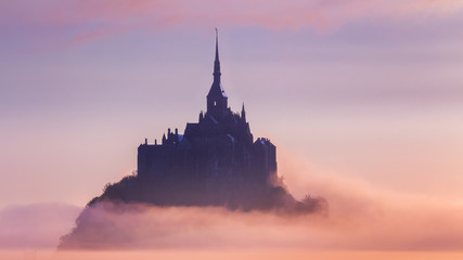 Panoramic view of famous Le Mont Saint-Michel tidal island in beautiful sunrise foggy light, Normandy, northern France - obrazy, fototapety, plakaty