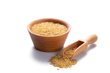 Bulgur in a wooden scoop and in a bowl isolated on white background