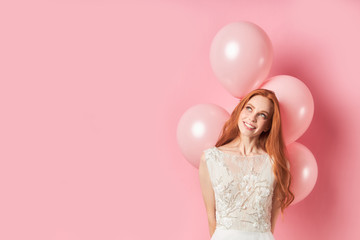 Portrait of smiling happy lady with long hair auburn, air balloons on pink background. People...