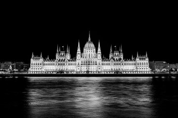Illuminated historical building of Hungarian Parliament at night on Danube River Embankment. Black white photo