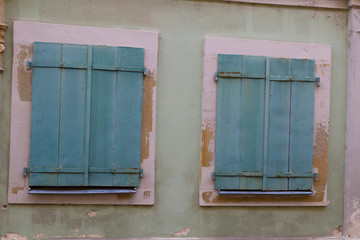 Two windows with closed wooden shutters