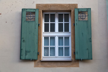 Fototapeta na wymiar Ancient colorful window with open wooden shutters on wall of house