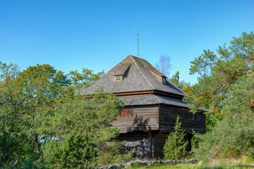 Well-preserved traditional wooden farmstead house made of resin-impregnated timbers at sunny autumn day. Stockholm, Sweden.