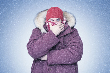 Frozen man in red winter clothes covers his face in the frost with his hand, cold, snow, blizzard