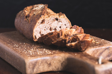 wholemeal bread sliced on a wooden board with a black background