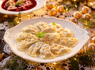 Christmas dumplings stuffed with forest mushrooms and cabbage on a white plate on a holiday table....
