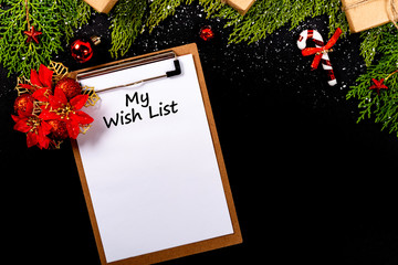 Christmas composition. Girlanda with Christmas ornaments and gifts on black background and blank notepad. Christmas, winter, new year concept. My Wish List © Julio Ricco