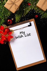 Christmas composition. Girlanda with Christmas ornaments and gifts on black background and blank notepad. Christmas, winter, new year concept. My Wish List © Julio Ricco