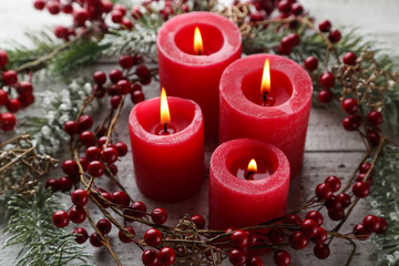 Christmas candles with red berries and fir tree branches on white wooden table