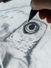 Drawing with gel pen on back lit fabric. Close up of technique to copy outline of an image onto fabric using a light box, for crafts such as collage quilting. Vertical.