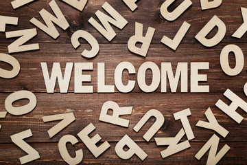 Word Welcome by wooden letters on brown table