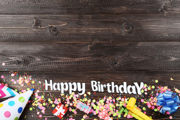 Fototapeta premium Text Happy Birthday with party decorations on wooden table