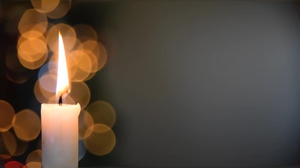 Burning Christmas candle with blinking light bokeh and copy space in the background
