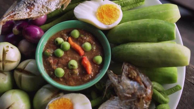 Set plate of fried mackerel with shrimp paste sauce and vegetables. Thai dish. slow motion. Top view clockwise rotate shot.