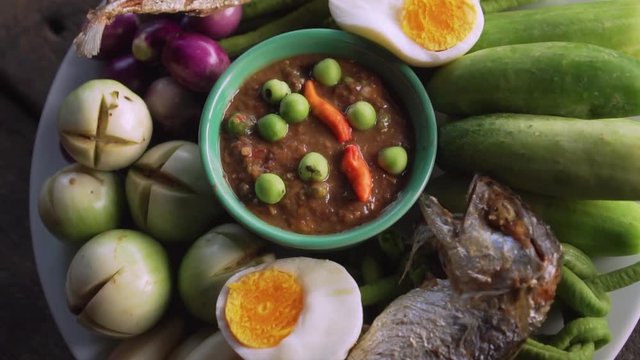 Set plate of fried mackerel with shrimp paste sauce and vegetables. Thai dish. slow motion. Top view counter-clockwise rotate shot.