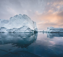 Fototapeta na wymiar Arctic nature landscape with icebergs in Greenland icefjord with midnight sun sunset sunrise in the horizon. Early morning summer alpenglow during midnight season. Ilulissat, West Greenland.