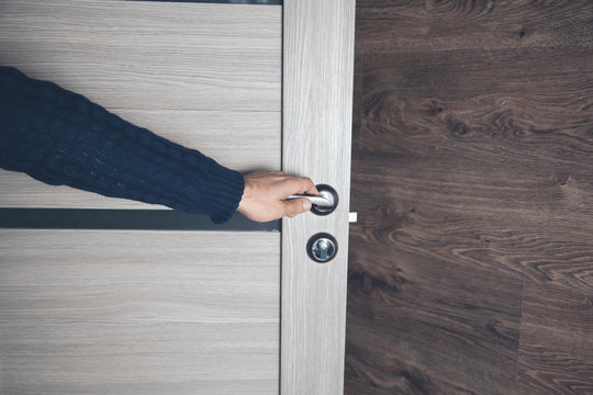 Young Man Opening Room Door On Brown Background