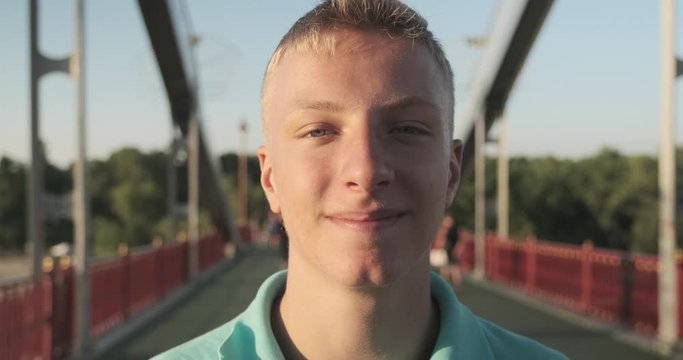 Smiling teenager 15, 16 years old blond boy posing looking at the camera