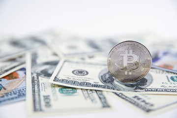 Bitcoin coin stands on hundred dollar bills