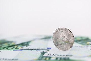 bitcoin coin on the background of one hundred euro bills