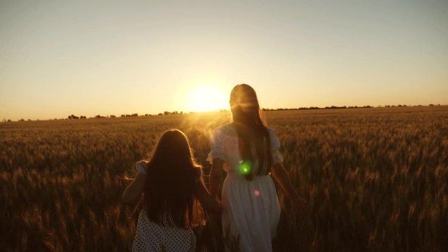 Mom gently hugs daughter against backdrop of beautiful sunset. adult daughter in arms of her mother in a field in the rays of the sun. mom strokes her daughter's hair.