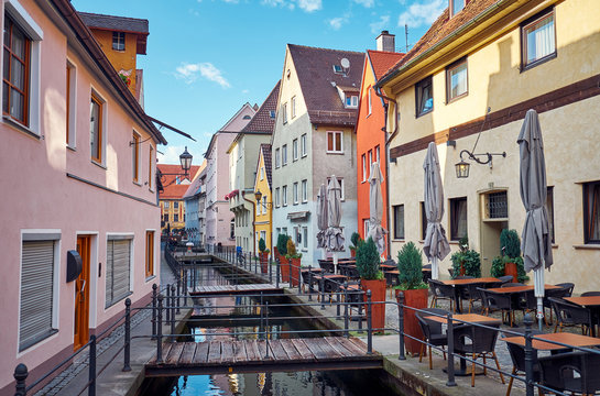 Old street with a water canal and restaurant in Memmingen.