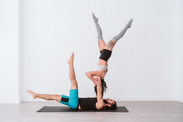 young couple Couple practicing acro yoga in white studio or gym. Healthy lifestyle