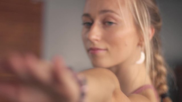 Closeup portrait with a soft focus while blonde woman makes a home werkout. Zoom out
