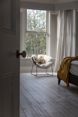 Fototapeta na wymiar Modern armchair covered in soft furnishings in a bright bedroom